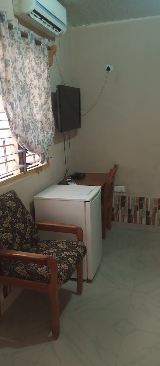 A MagJohn guest room with air conditioning, television, refrigerator and seating